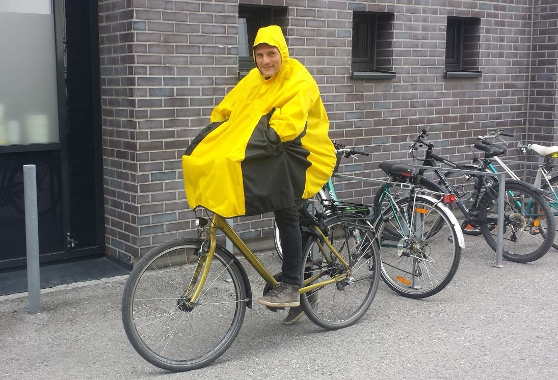 Ein Mann in einem gelben Regenmantel auf einem Fahrrad